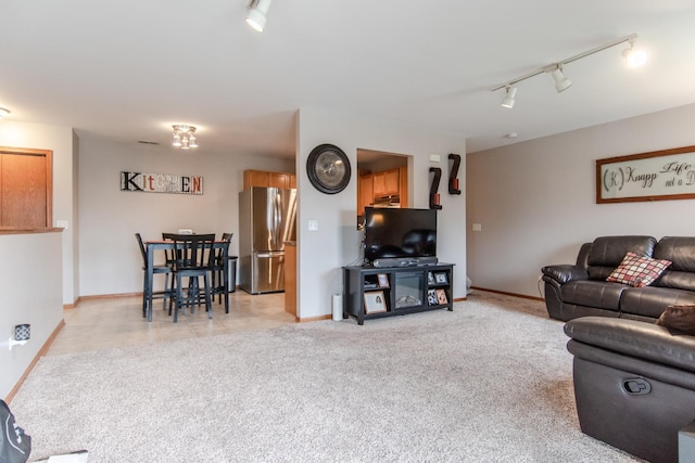 living area with light carpet, baseboards, and rail lighting