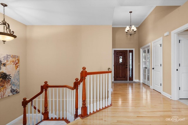 foyer entrance with wood finished floors, a chandelier, baseboards, and a high ceiling