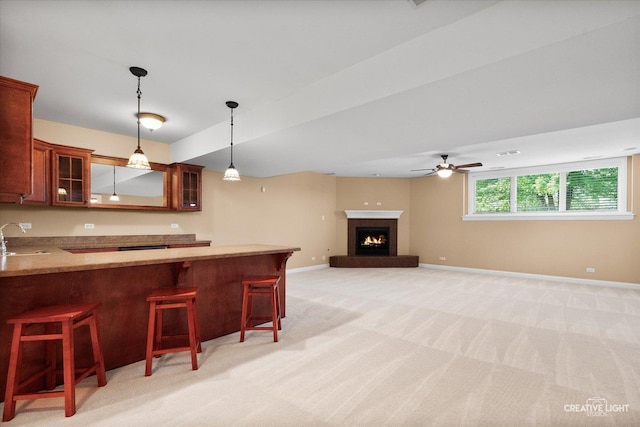 kitchen with a sink, pendant lighting, glass insert cabinets, a breakfast bar area, and baseboards