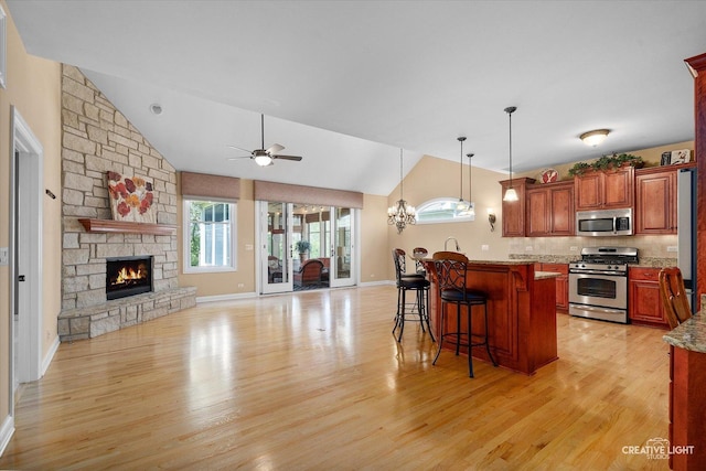 kitchen with stainless steel appliances, vaulted ceiling, a kitchen breakfast bar, light wood finished floors, and open floor plan