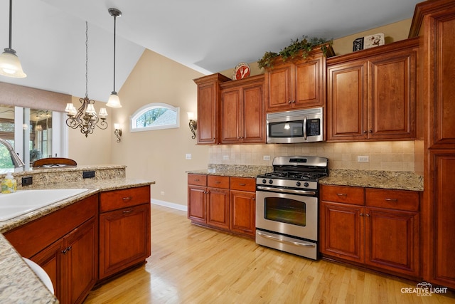 kitchen with appliances with stainless steel finishes, a sink, light wood-type flooring, backsplash, and lofted ceiling