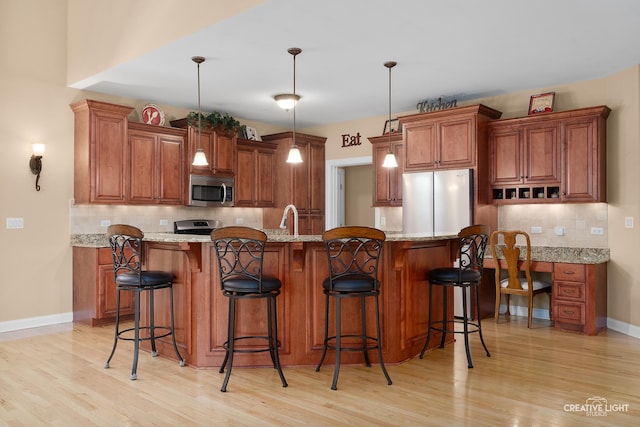 kitchen with appliances with stainless steel finishes, brown cabinets, and light wood finished floors
