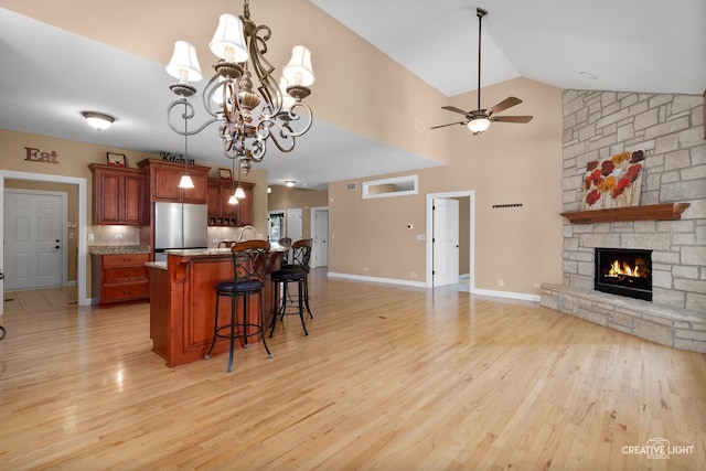 kitchen with freestanding refrigerator, open floor plan, light wood-type flooring, a kitchen breakfast bar, and ceiling fan