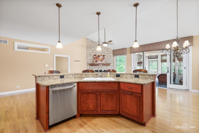 kitchen featuring a sink, dishwasher, lofted ceiling, light wood-type flooring, and a stone fireplace