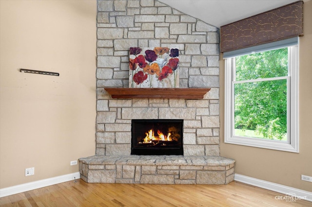 detailed view of a fireplace, wood finished floors, and baseboards