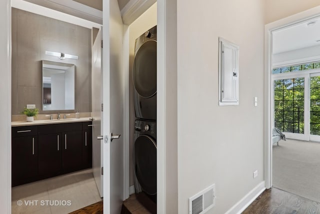 clothes washing area featuring laundry area, visible vents, electric panel, a sink, and stacked washer / drying machine