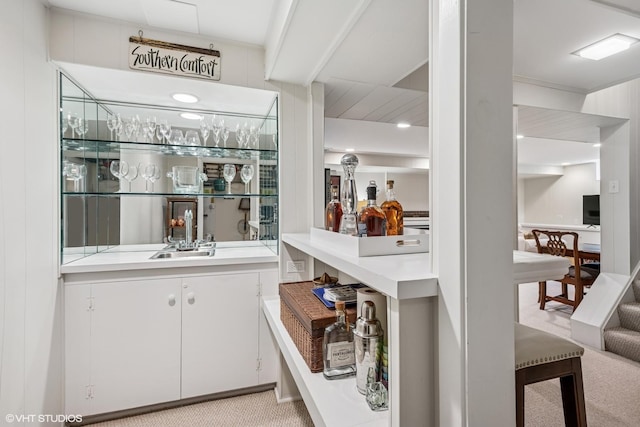 bar featuring a sink, indoor wet bar, and light colored carpet