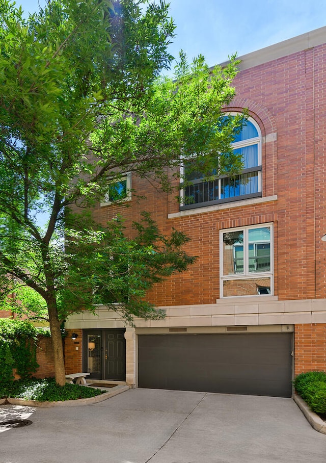 view of front of house with an attached garage, driveway, and brick siding