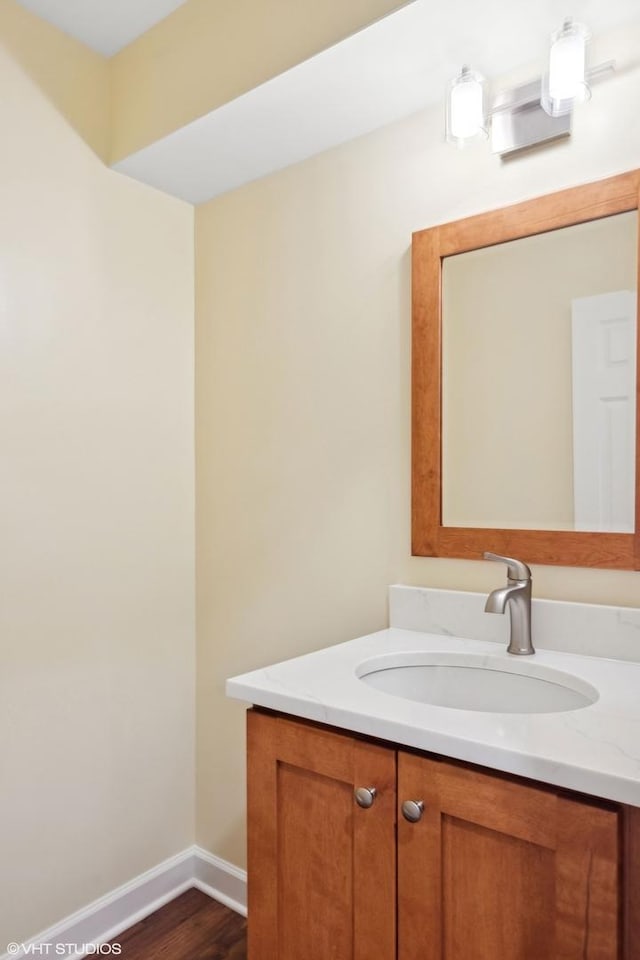 bathroom featuring baseboards, wood finished floors, and vanity