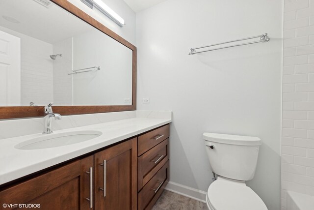 bathroom featuring baseboards, toilet, and vanity