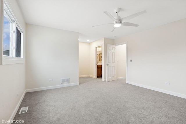 spare room featuring light carpet, a ceiling fan, and visible vents
