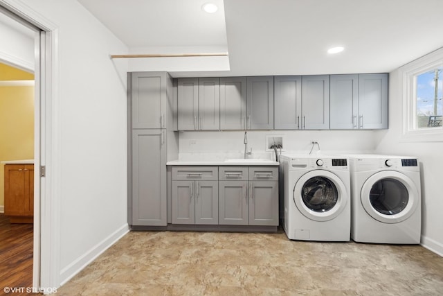 washroom featuring washing machine and dryer, baseboards, a sink, and cabinet space