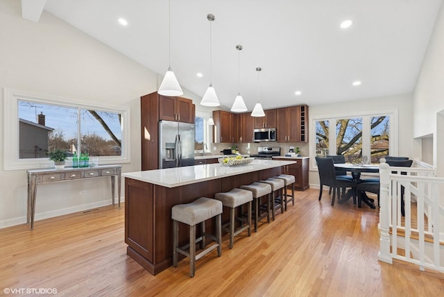 kitchen featuring light countertops, light wood-type flooring, appliances with stainless steel finishes, and a breakfast bar area