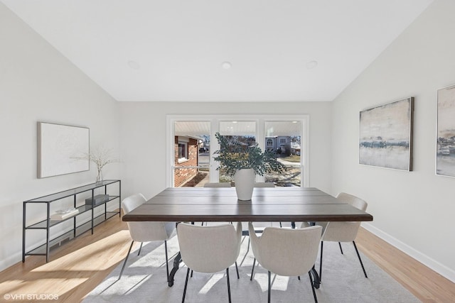 dining area with lofted ceiling, baseboards, and light wood-style flooring