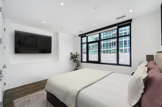 bedroom with baseboards, wood finished floors, visible vents, and recessed lighting