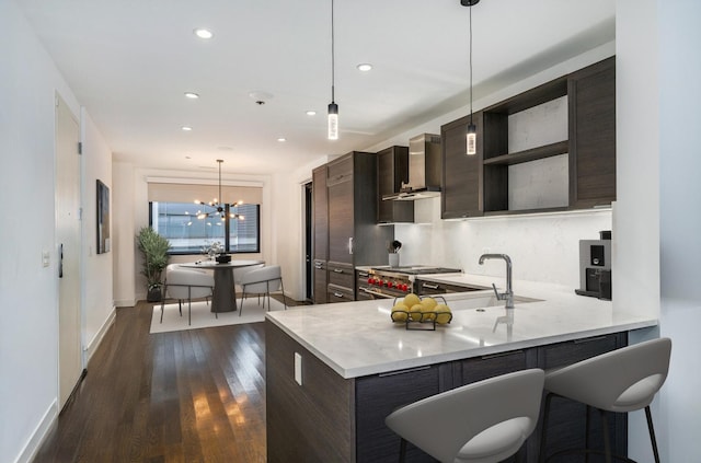 kitchen featuring dark wood finished floors, light countertops, dark brown cabinets, wall chimney exhaust hood, and stainless steel stove