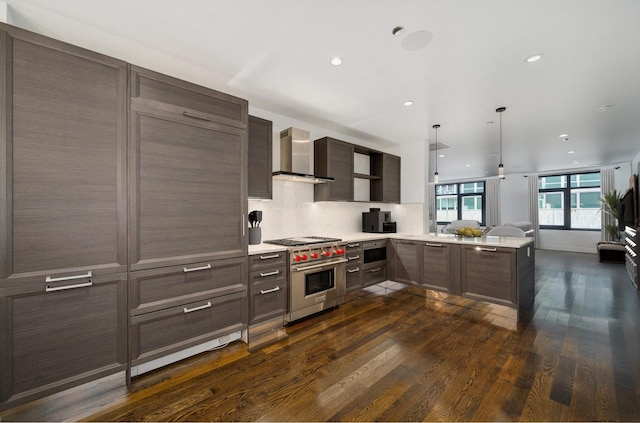 kitchen featuring wall chimney exhaust hood, dark wood finished floors, open floor plan, luxury range, and light countertops