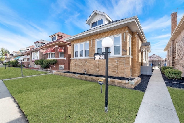 bungalow-style home featuring fence, a front lawn, and brick siding