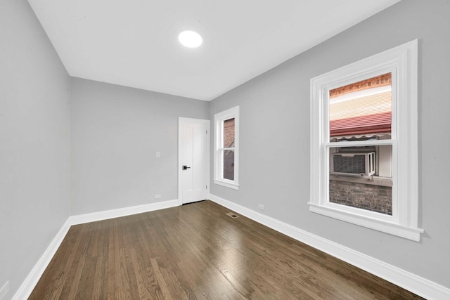 unfurnished room featuring baseboards, dark wood-type flooring, and visible vents