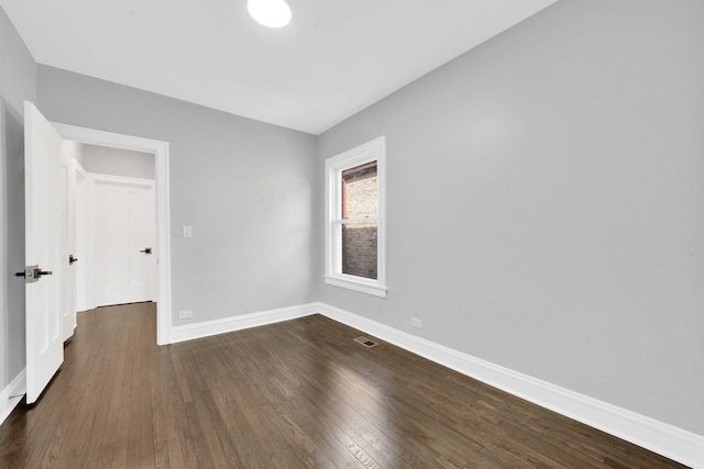 unfurnished room with dark wood finished floors, visible vents, and baseboards