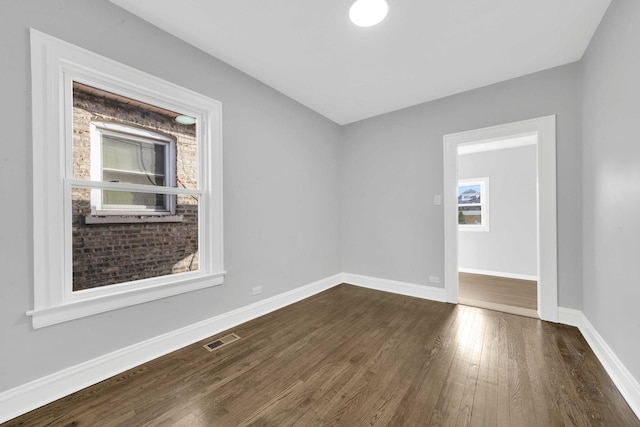 empty room featuring baseboards, visible vents, and dark wood finished floors