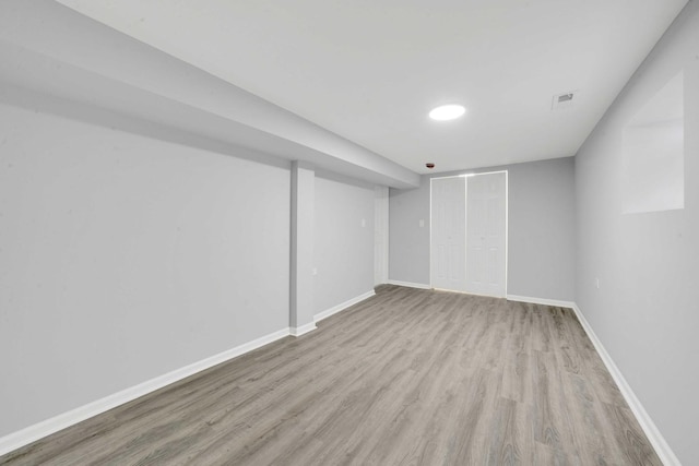 finished basement with baseboards, wood finished floors, and visible vents