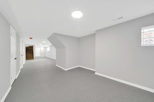 additional living space with baseboards and visible vents