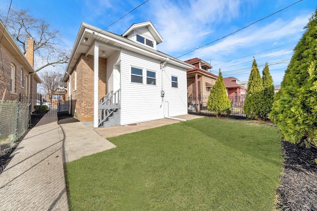 rear view of house featuring brick siding, a yard, entry steps, and fence