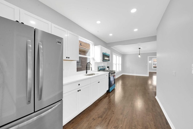 kitchen featuring dark wood finished floors, a sink, baseboards, appliances with stainless steel finishes, and white cabinetry