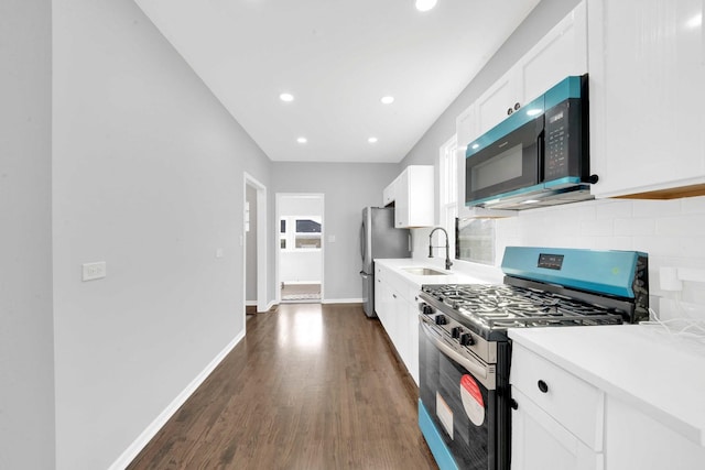 kitchen with white cabinets, backsplash, a sink, appliances with stainless steel finishes, and dark wood-style flooring