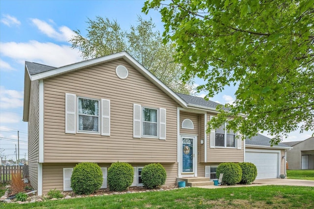 bi-level home with fence, driveway, and a front yard