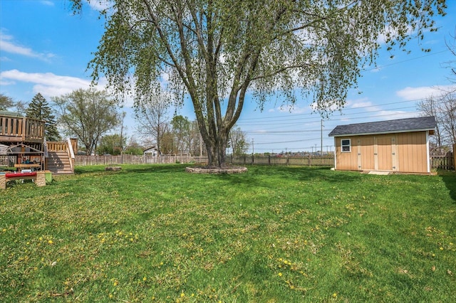 view of yard featuring a deck, an outbuilding, a shed, a fenced backyard, and stairs