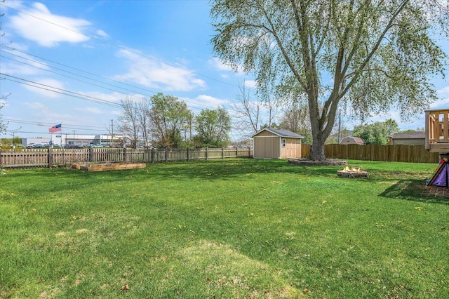 view of yard featuring a storage unit, a fenced backyard, an outdoor fire pit, and an outdoor structure