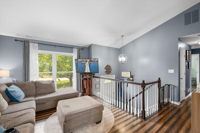 living area with visible vents, vaulted ceiling, wood finished floors, baseboards, and an inviting chandelier