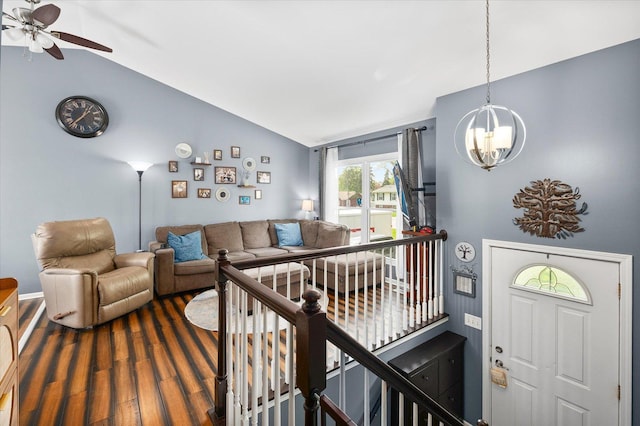 living area with ceiling fan with notable chandelier, vaulted ceiling, and dark wood-type flooring