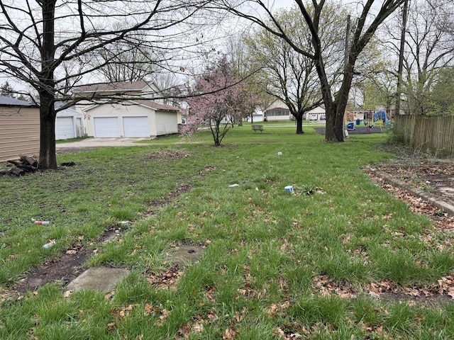view of yard with fence, an outbuilding, and a detached garage