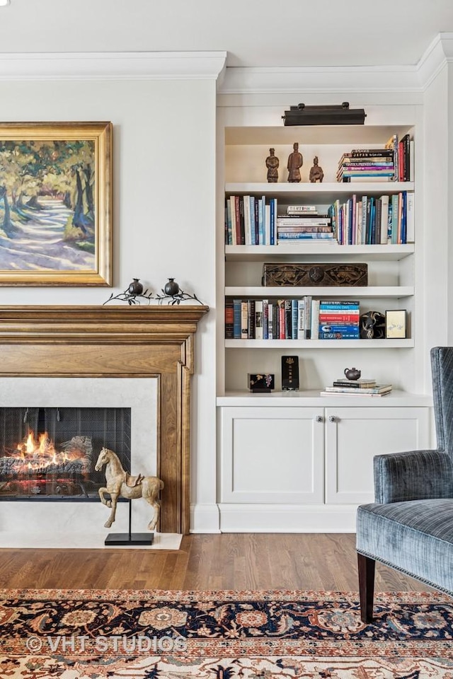 living area with ornamental molding, wood finished floors, and a premium fireplace