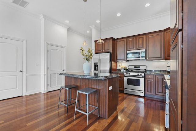 kitchen with stainless steel appliances, dark wood finished floors, a kitchen island, crown molding, and a breakfast bar area
