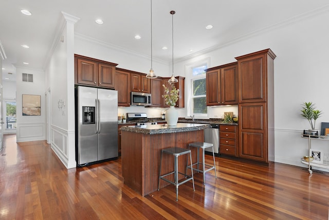 kitchen featuring stainless steel appliances, dark wood finished floors, a center island, decorative light fixtures, and ornamental molding