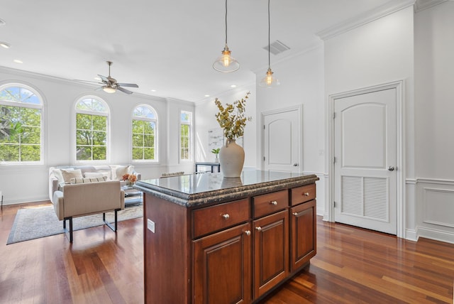 kitchen with ornamental molding, a ceiling fan, dark wood-style flooring, decorative light fixtures, and open floor plan