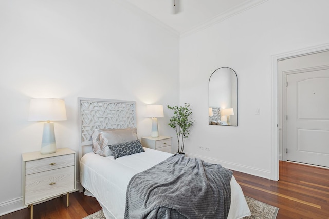 bedroom with crown molding, wood finished floors, and baseboards