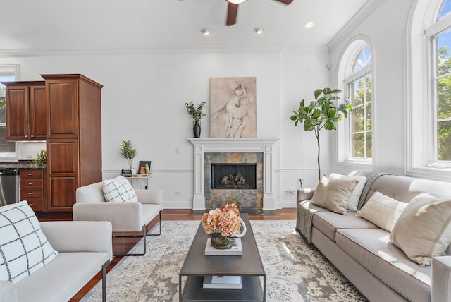 living area featuring healthy amount of natural light, ceiling fan, wood finished floors, ornamental molding, and recessed lighting