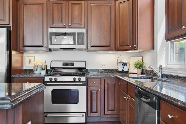 kitchen with stainless steel appliances, a sink, and dark stone countertops