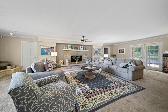 living room featuring carpet flooring, crown molding, a ceiling fan, and a stone fireplace