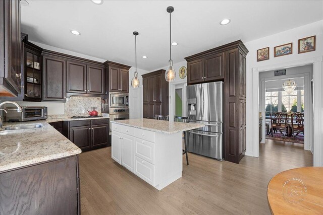 1651 Eagle Brook Dr, Geneva, IL 60134 - kitchen with light wood finished floors, stainless steel appliances, a sink, dark brown cabinetry, and decorative backsplash