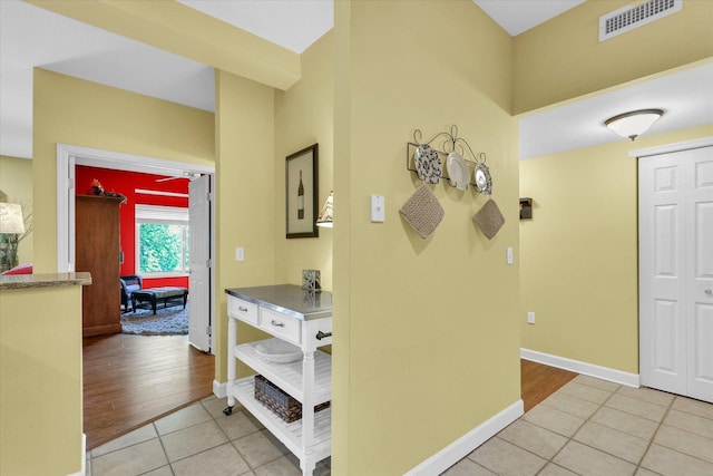 hallway featuring visible vents, baseboards, and tile patterned flooring