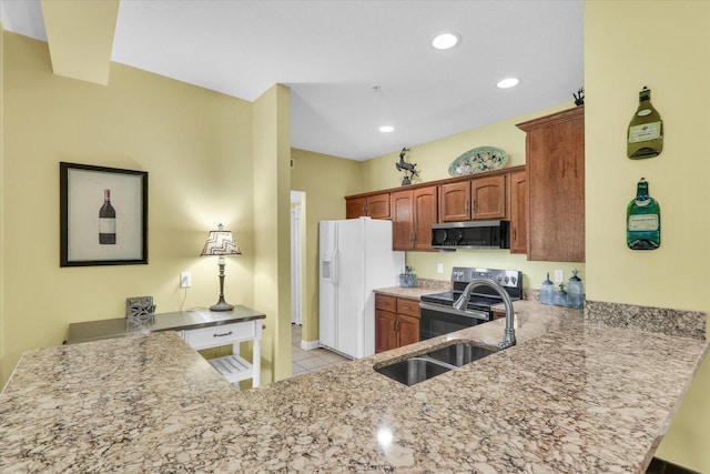 kitchen with a peninsula, appliances with stainless steel finishes, light stone counters, and light tile patterned floors