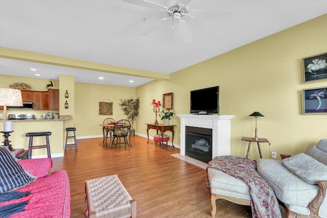 living room with a fireplace with flush hearth, recessed lighting, ceiling fan, and light wood-type flooring