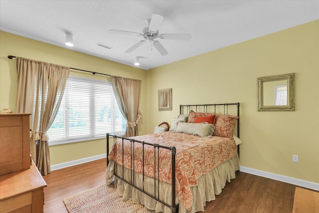 bedroom featuring a ceiling fan, baseboards, visible vents, and wood finished floors