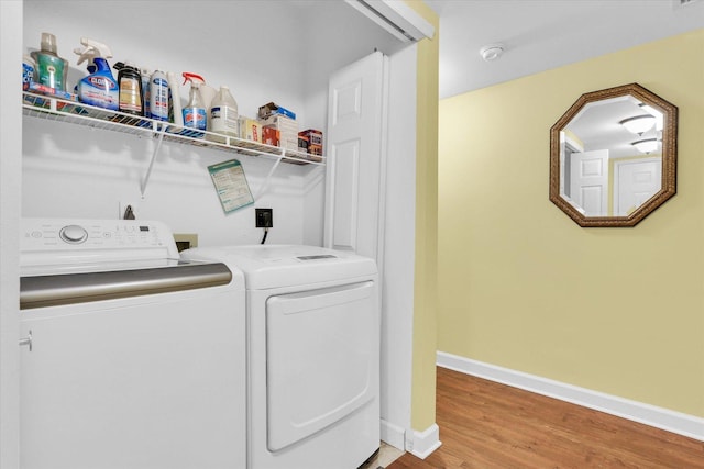 clothes washing area with baseboards, laundry area, wood finished floors, and washing machine and clothes dryer